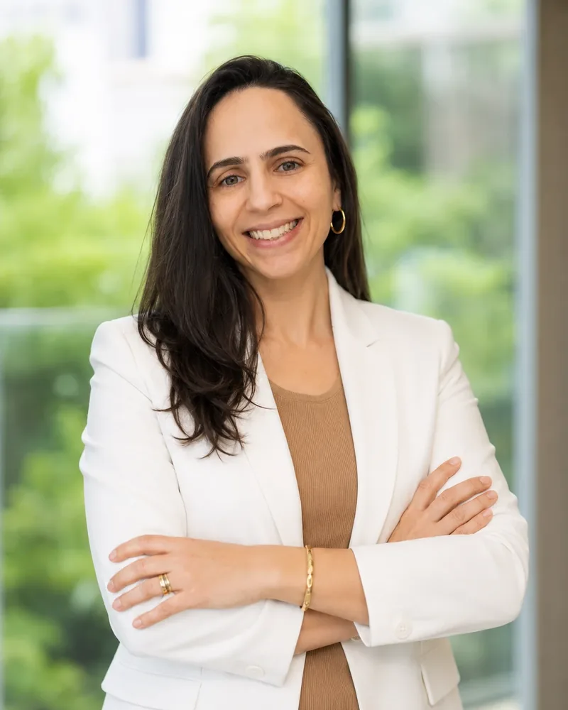 Aline Pianti, de blazer branco e braços cruzados, sorrindo
